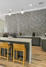 A kitchen with a stone backsplash and wooden chairs.