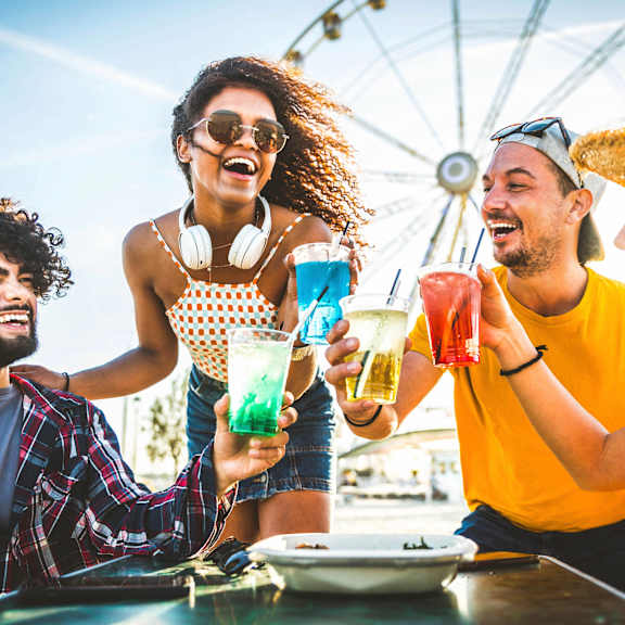 group of friends drinking drinks at an amusement park