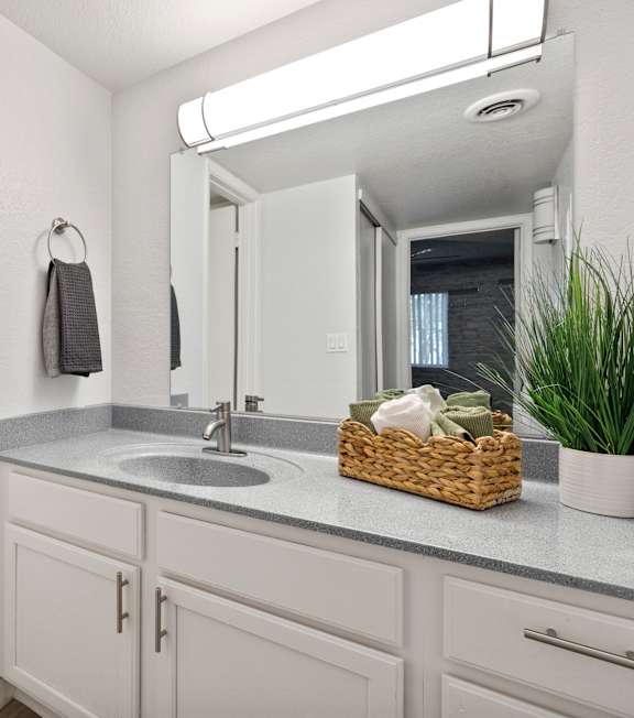 a bathroom with white cabinets and a sink and a mirror