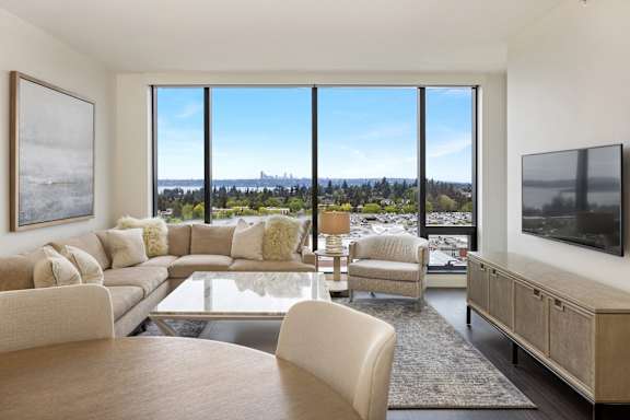 a living room with a couch and a table and a view of the city at Two Lincoln Tower Apartments, Bellevue, WA, 98004