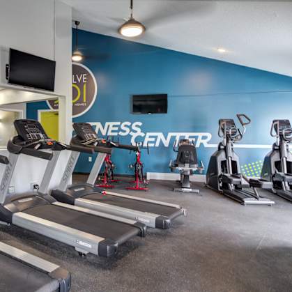 a room filled with cardio equipment and a flat screen tv