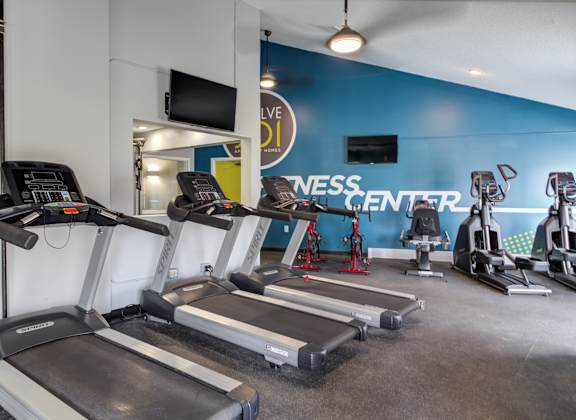 a room filled with cardio equipment and a flat screen tv
