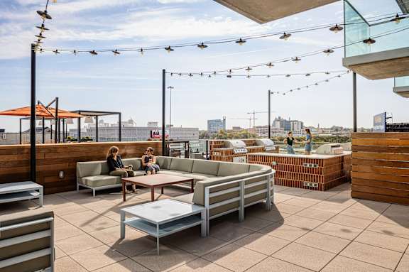 Two people sit on a patio with a table and chairs.