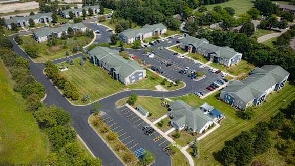 A bird's eye view of a parking lot surrounded by green grass and buildings.