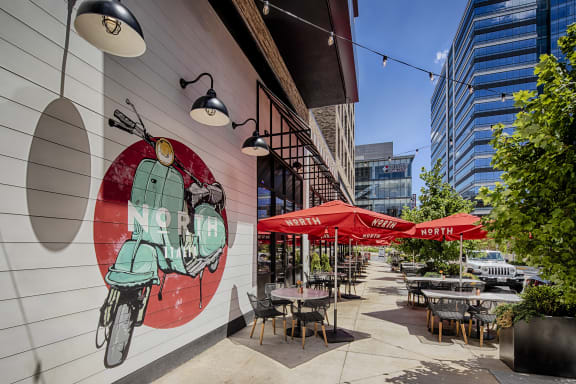 a patio with tables and umbrellas and a mural of a motor scooter