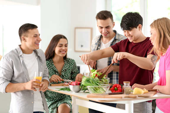 A group of people are gathered around a table, preparing food together.