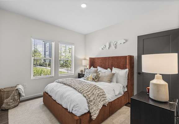 a bedroom with a large bed and two windows