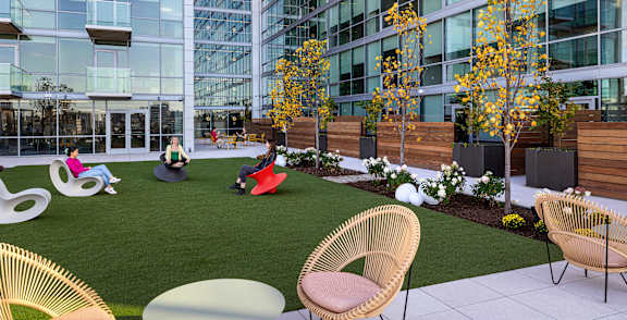 A green space with people walking and sitting on chairs.