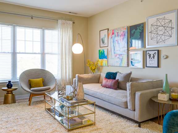 A living room with a beige couch, a yellow chair, and a glass coffee table.
