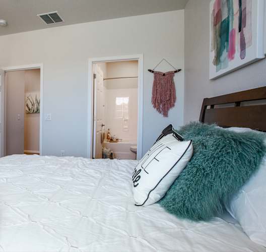 a bedroom with a white bedspread and a pink blanket