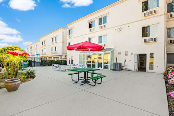 A patio with a table and chairs and a building in the background.