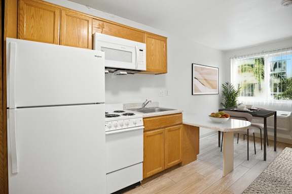 A kitchen with a white refrigerator, white oven, and a white microwave.