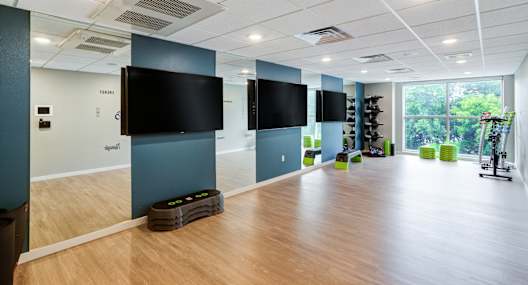 a large room with a wood floor and large flat screen televisions on the wall