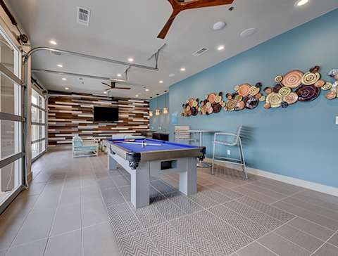 A pool table is in the middle of a room with a TV and a chair at Estraya Westover Hills, San Antonio, Texas