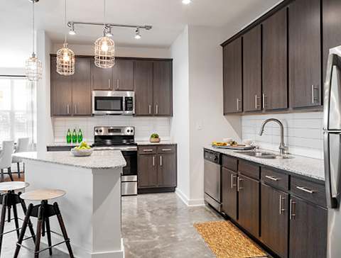 A modern kitchen with dark brown cabinets and a white island at Robley Place, Lafayette, LA, 70503