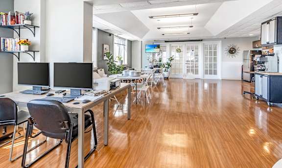 A room with a desk and chairs with a computer on it.