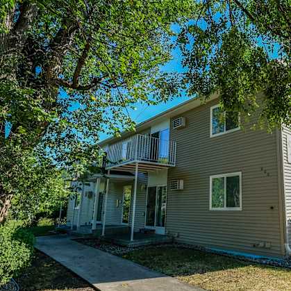 the front of a house with trees and a sidewalk