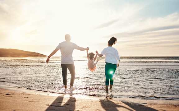 A couple holding hands and walking on the beach.