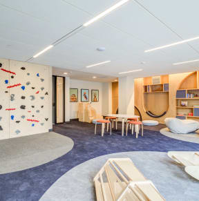 a room with a rock climbing wall and a table and chairs