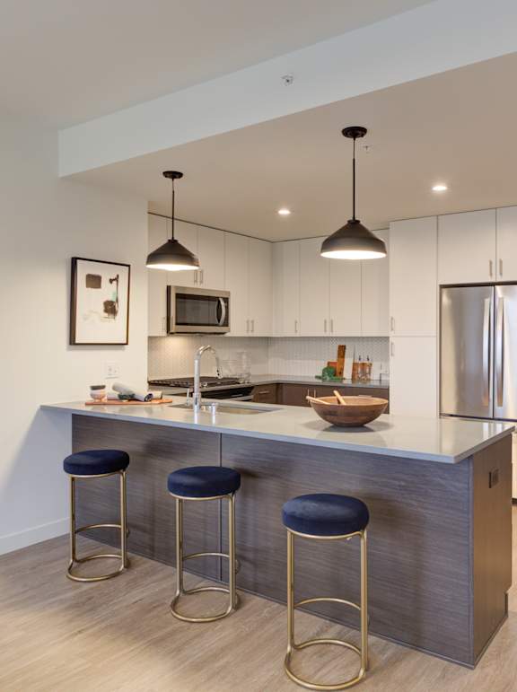 A modern kitchen with a bar stool and a refrigerator.