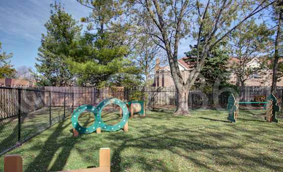 A playground with a green slide and a brown bench.