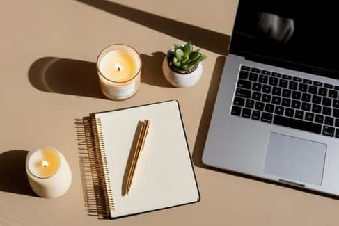 A laptop, a notebook, a pen, and two candles are arranged on a table at Masselin Park West, California, 90036