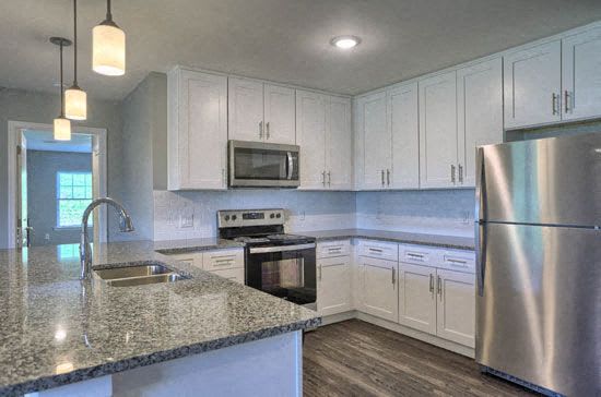 a kitchen with white cabinets and a granite counter top