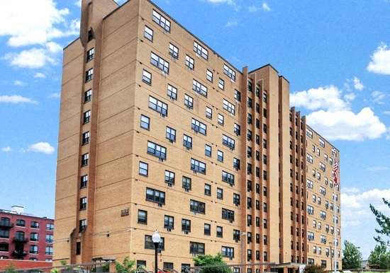 a tall brown building with many windows and a blue sky