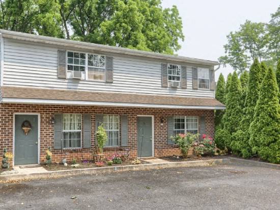 a brick house with blue doors and a parking lot