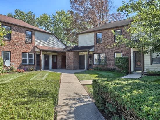 front view of a brick house with a sidewalk and grass