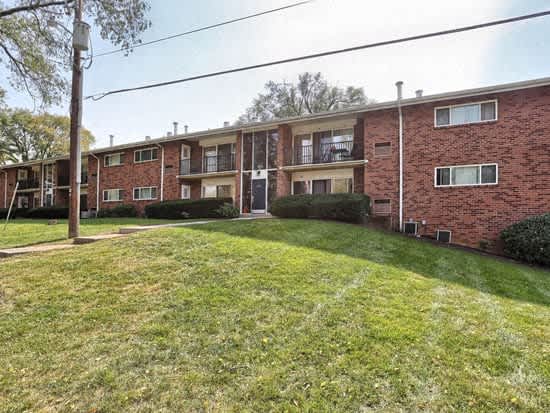 a red brick apartment building with a grassy yard