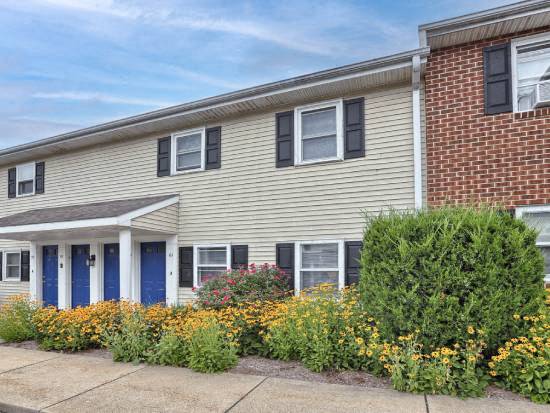 a white house with blue doors and a flower garden