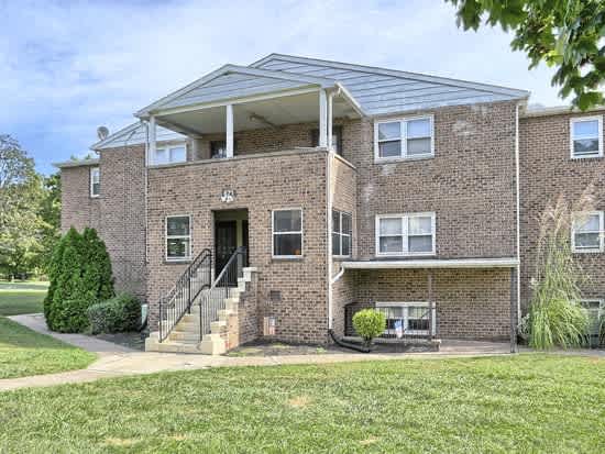 a brick house with a front porch and a lawn