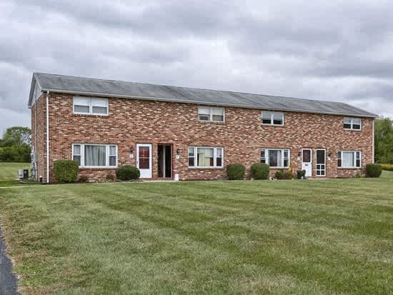 a red brick house with a green lawn in front of it