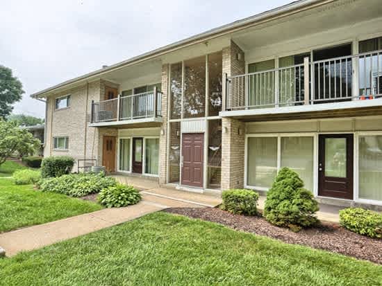 the front of an apartment building with a yard and a balcony