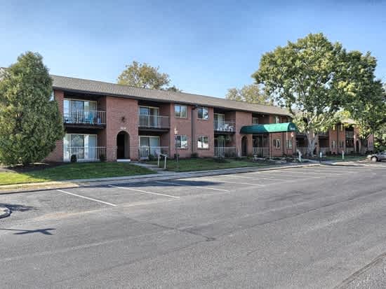 a red brick apartment building with balconies and a parking lot