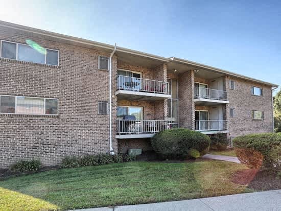 a brick apartment building with two balconies and a lawn