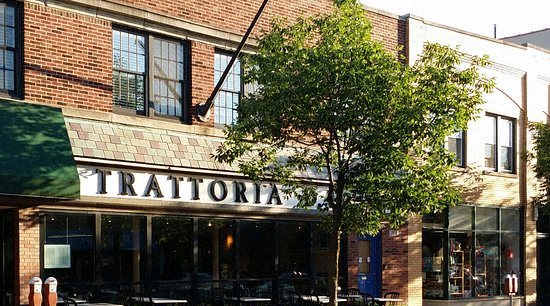 A brick building with a green awning and the word "Trattoria" on it.