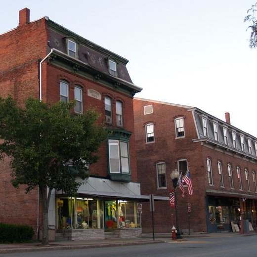 A red brick building with a green awning and an American flag on a pole in front of it.