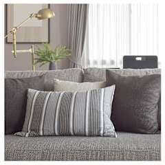 A grey couch with striped pillows and a laptop on the back.