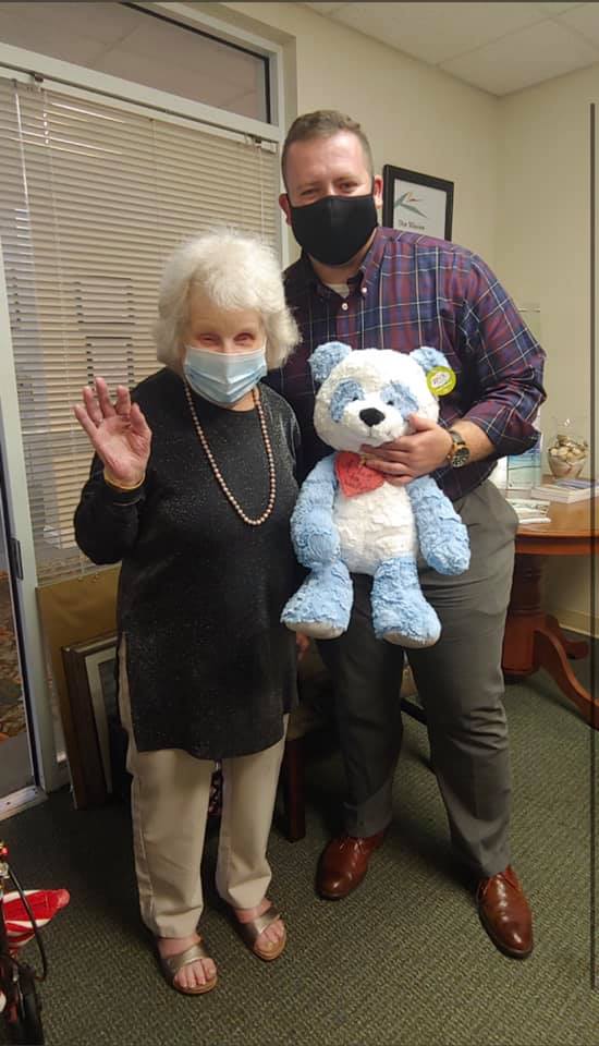 a man and woman wearing masks and holding a teddy bear