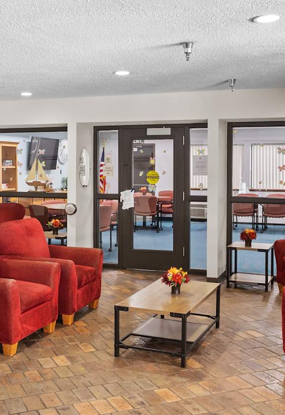 A living room with red chairs and a wooden floor.