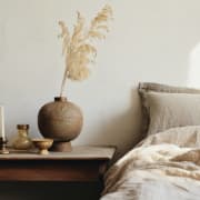 a bed with pillows and a table with a vase and a candle