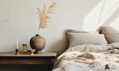 a bed with pillows and a table with a vase and a candle