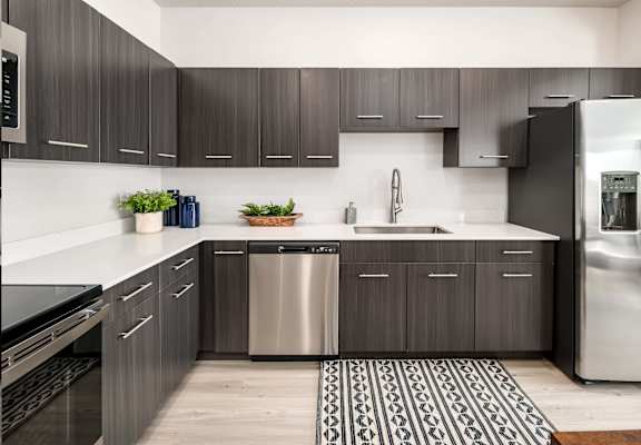 A modern kitchen with dark wood cabinets and stainless steel appliances.