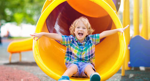 A child is sliding down a yellow slide.