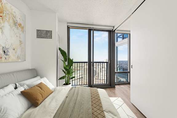 A bedroom with a large bed and a view of the city through the window.