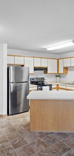 A kitchen with a refrigerator, sink, and cabinets.
