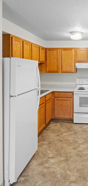 A kitchen with white appliances and wooden cabinets.