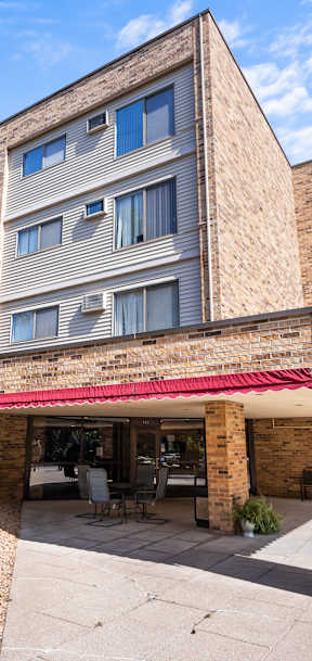 A building with a red awning and a parking lot in front.